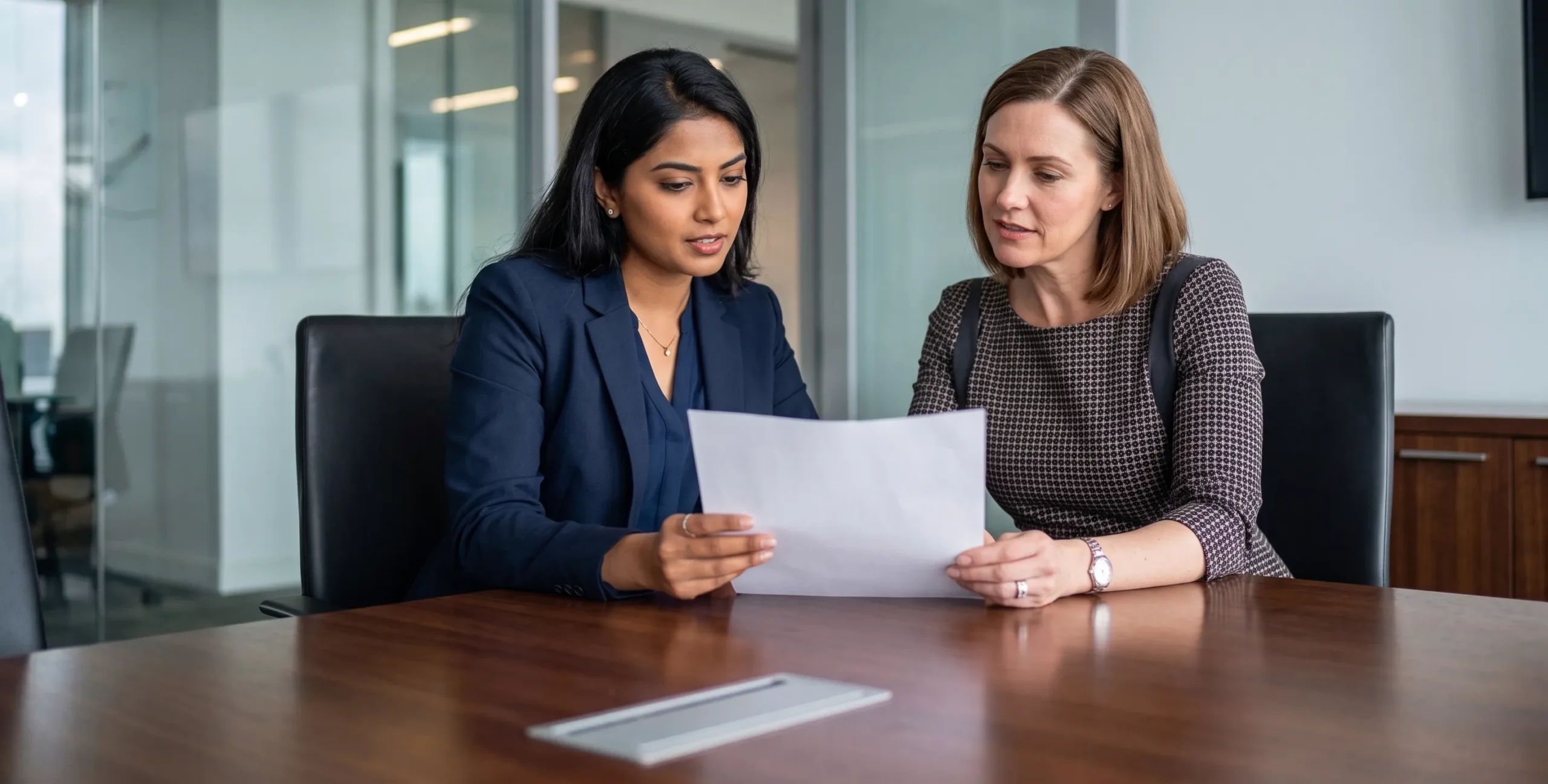 two diverse business professionals reviewing documents together, modern co-working office, bright ed